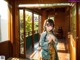 A woman in a blue kimono standing in front of a door.