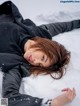 A woman laying in the snow with her eyes closed.