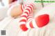 A woman laying on a bed with red and white striped stockings.