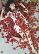 A woman laying on the ground covered in red rose petals.