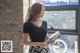 A woman standing in front of a window holding a magazine.